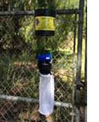 CO2 mosquito trap installation on a chain-link fence in a wooded area.