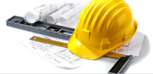 Yellow construction hard hat, spirit level, folding ruler, and architectural blueprints on a white background