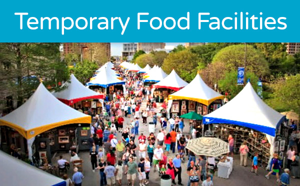 A bustling outdoor food market with multiple white-canopied stalls and a diverse crowd of visitors.