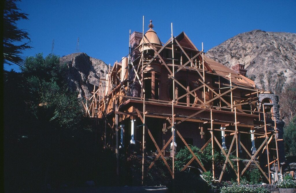 Two-story home under restoration with wooden scaffolding against a mountainous backdrop