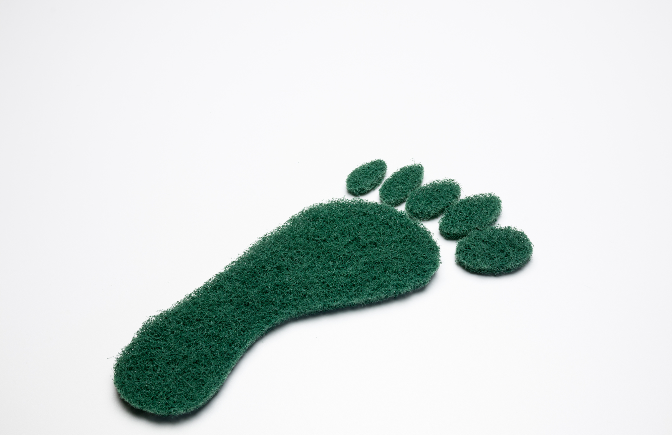 Green footprint-shaped scrubber on white background.