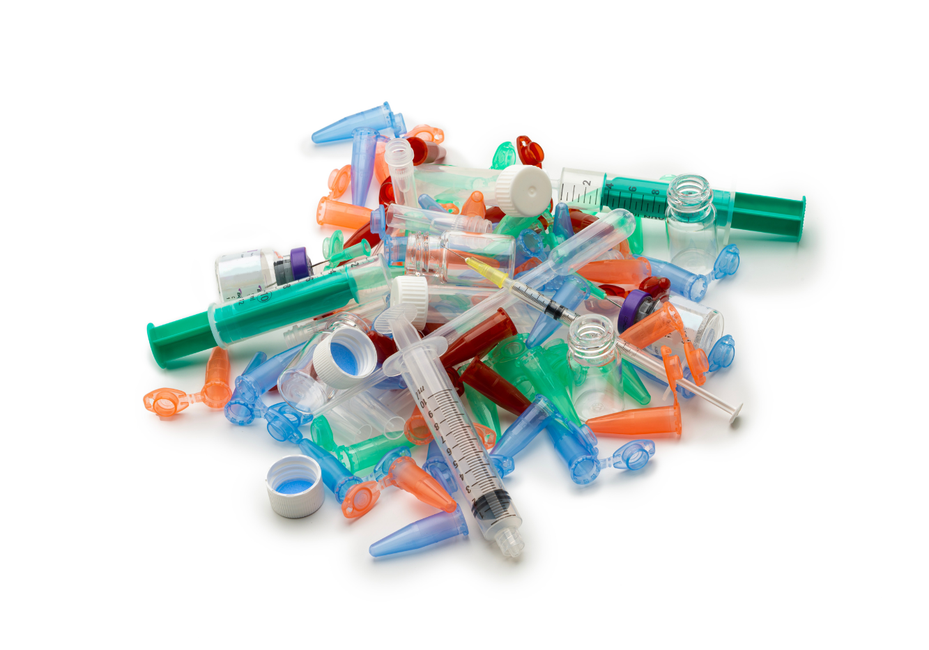 A pile of various medical plastic waste including syringes, vial caps, and small tubes.