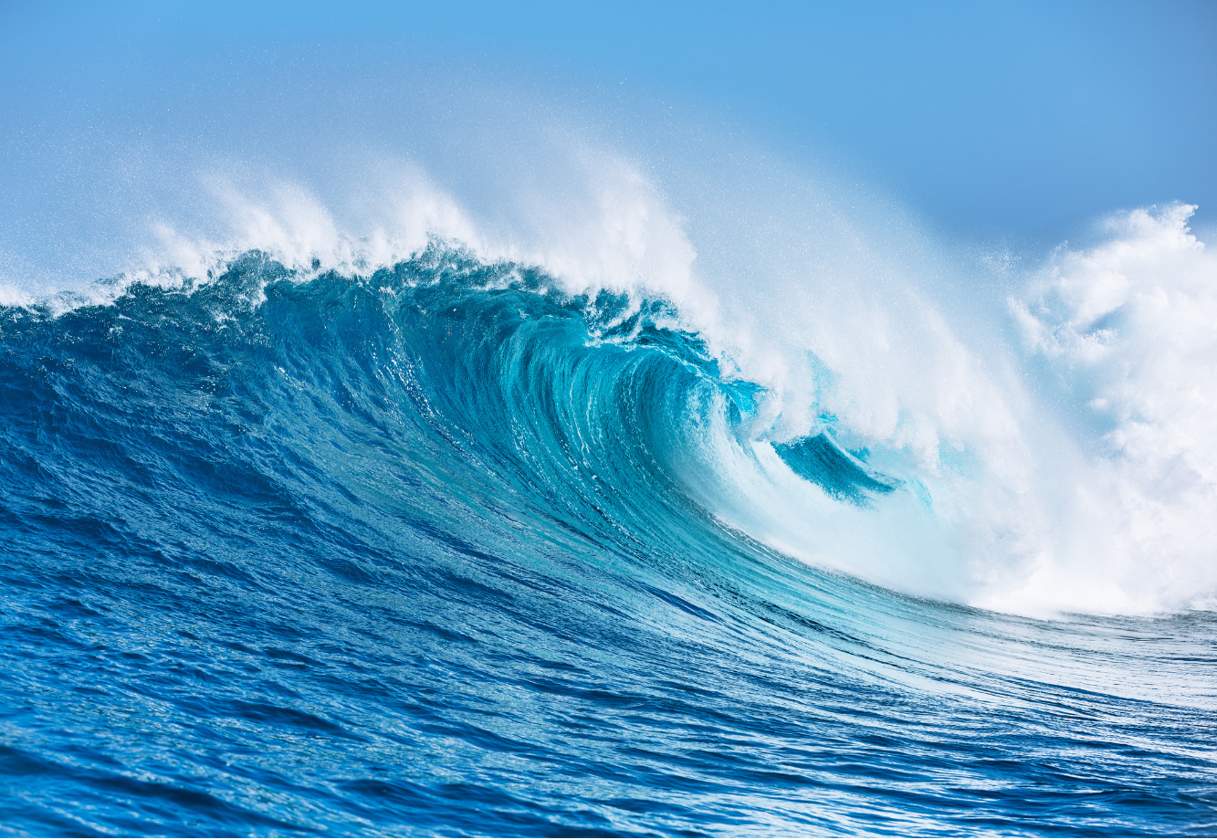 Large ocean wave against a clear blue sky.