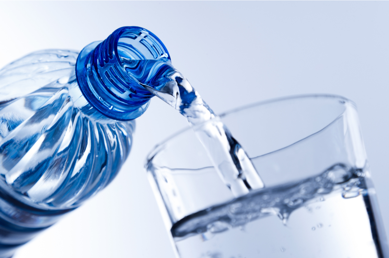 Water being poured from a plastic bottle into a glass.