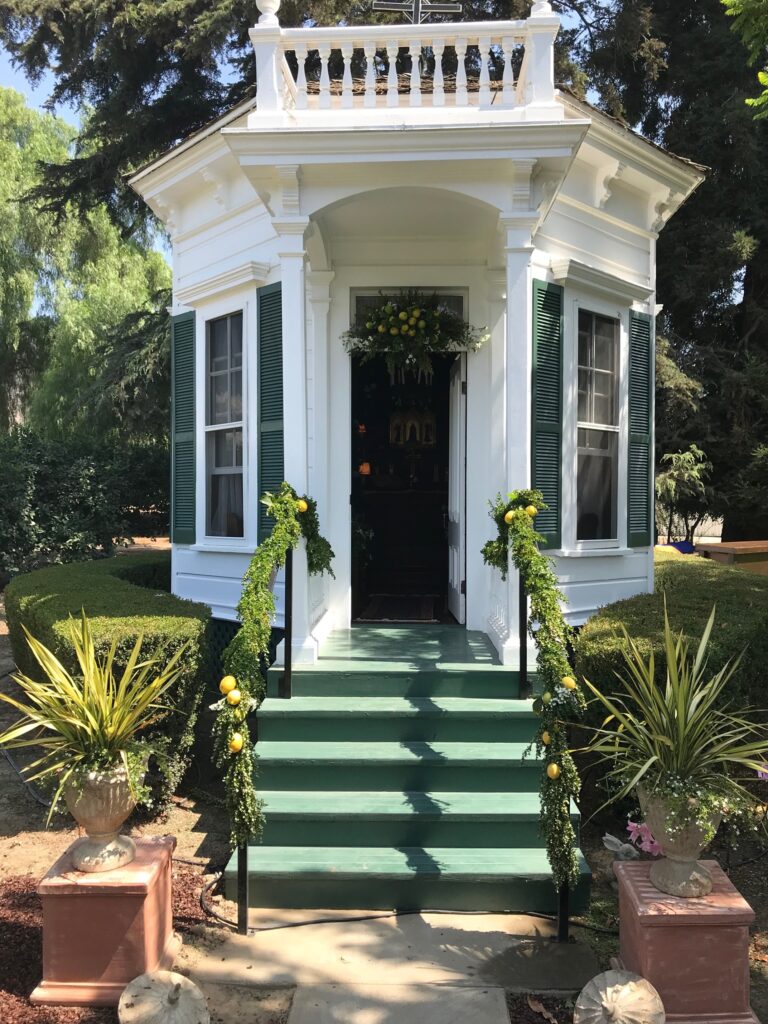 Front view of a small white chapel building with green steps and trim.